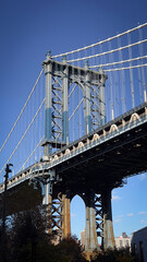 Obraz premium A detailed view of the Manhattan Bridge structure under a clear blue sky, showcasing its iconic steel design and urban significance.