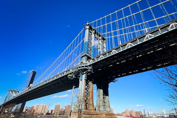 Fototapeta premium A detailed view of the Manhattan Bridge structure under a clear blue sky, showcasing its iconic steel design and urban significance.