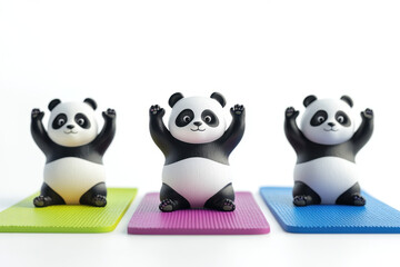 Three adorable panda figurines sitting on colorful yoga mats with raised arms, creating a playful and cheerful atmosphere.