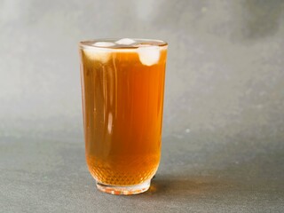 A refreshing glass of iced tea, elegantly served in a crystal clear glass. The amber hue of the iced tea contrasts beautifully with the clarity of the glass. A classic iced tea, isolated gray