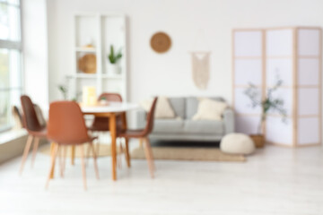 Interior of stylish living room with comfortable sofa and dining table. Blurred view