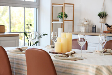Candles on served dining table in kitchen