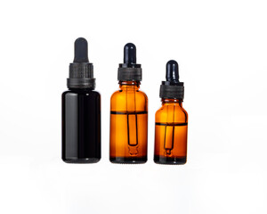 Natural cosmetics facial serum in three dark glass bottles with dropper for daily grooming. isolated on white