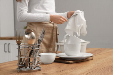 Woman wiping clean dishes with napkin in kitchen