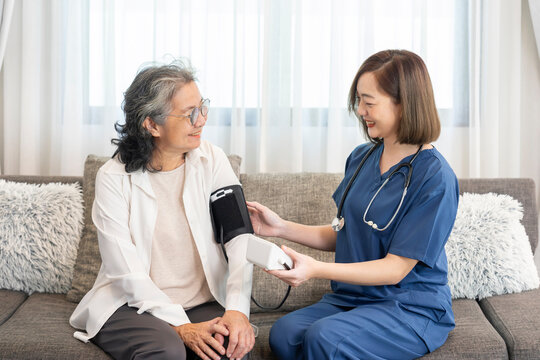 visiting nurse taking care senior woman at home,taking vital signs,blood pressure,notify the result and giving advice,concept of elderly health care,home health care services,health insurance