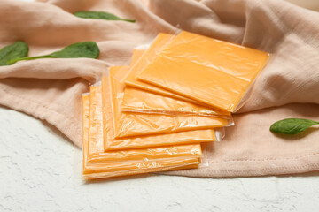 Slices of delicious processed cheese and fresh spinach on white grunge table