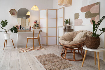 Interior of light dressing room with makeup table, folding screen and armchair