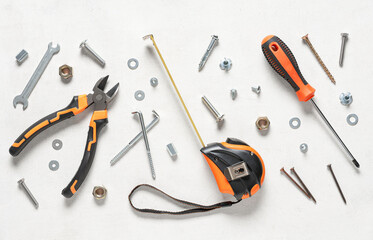 Tools with tap bolts, screws and chrome nuts on white grunge background