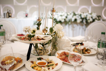 The festive table with dishes and drinks is decorated with candles and flowers.