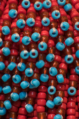 Dettaglio di alcune perline di plastica rosse e azzurre legate insieme © Andrea Vismara