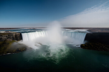 Fototapeta premium Niagara Falls in winter is a stunning sight, with frozen water, snow-covered surroundings, and mist creating sparkling ice crystals, offering a serene and magical atmosphere
