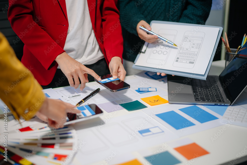 Wall mural close up view of ui developer team brainstorming on their project with laptop, smartphone and digita