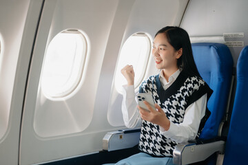 Young Asian executive excels in first class, multitasking with digital tablet, laptop and...