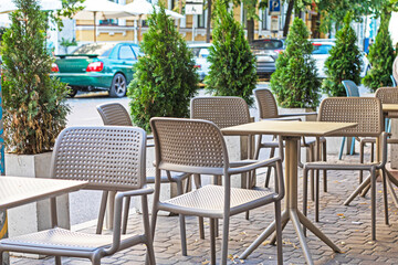 street cafe with wicker furniture and green thujas along the road