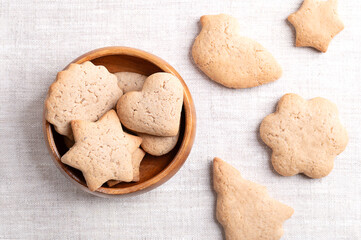 Homemade gingerbread cookies in a wooden bowl on linen fabric. Sweet, light brown and flat baked...