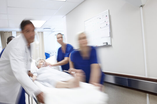 Medical, team and rushing with patient in hospital for healthcare emergency or surgery urgency. Motion blur, doctor group or running with stretcher for intensive care, ICU treatment or health support