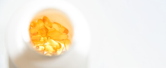 Vitamins food supplement Omega-3 fish oil softgel pills inside a white bottle. Natural sunlight top view shot with copy space. Essential nutrients fatty acids good for ADHD, brain and healthy body.