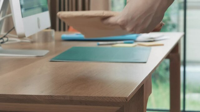 A desk with a computer monitor, a red chair, a green mat, a cup, a tablet, and a stack of papers