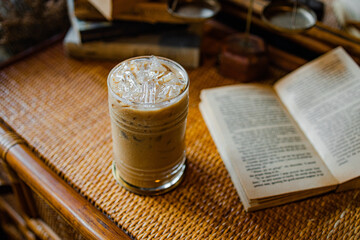A cozy scene featuring a glass of iced coffee beside an open book on a textured tabletop.