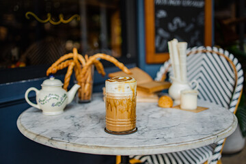 A stylish café table featuring a beverage, a teapot, decorative items, and breadsticks, set against a chic backdrop.
