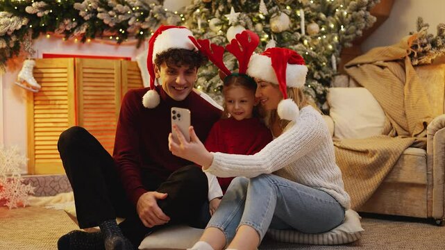 Happy family wearing Christmas accessories calls relatives to share holiday joy