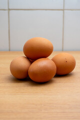Fresh brown eggs on a rustic wooden kitchen countertop, illuminated by soft natural light, creating a warm and homely atmosphere. Perfect for food and farm-to-table concepts.