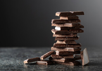 Broken bitter chocolate bar on a black background.
