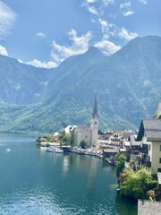 Charming hallstatt village surrounded by a peaceful lake, with a striking church spire reaching...