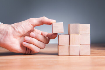 man hand holding wooden block with wooden blocks on white background, business and success concept.