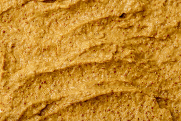 Mustard sauce with grains close-up. Hot spices as a background. Texture of Dijon mustard.