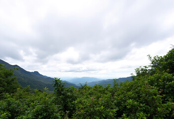 A scenic view of a mountainous landscape with a cloudy sky in the background