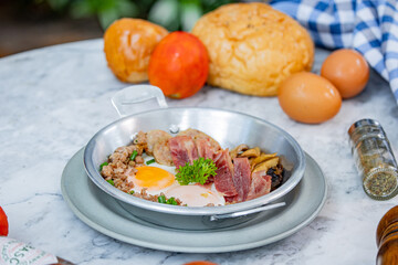 A delicious breakfast plate featuring eggs, bacon, and grains, complemented by fresh bread and tomatoes, perfect for a hearty meal.