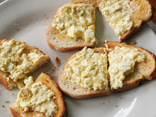 Close up of some egg mayonnaise on toasted white bread on a white porcelain plate