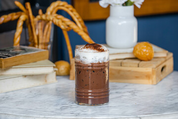 A delicious chocolate drink topped with cream, set against a cozy background of books and decor, perfect for coffee lovers.