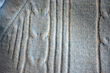 Knitted products, light blue women's woolen sweater with interesting patterns, knitting in the form of a braid, gathered elastic, different weaves and stitching.