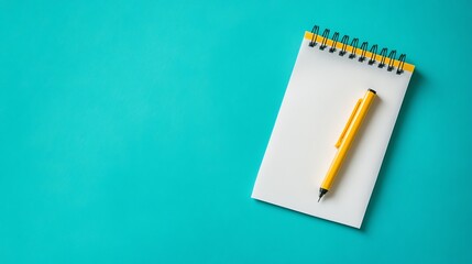 A yellow pen lies on a blank notepad, which is on a teal background.