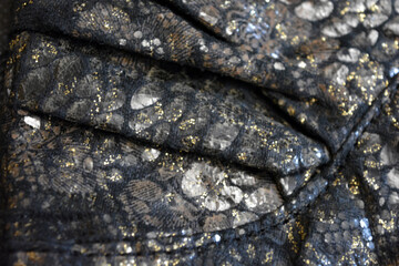 Black dark fabric background with gilding, gold flower patterns with reflective plastic scales.