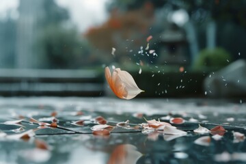 Obraz premium A single petal floats gracefully amid a soft blur of rain and greenery, capturing a serene moment of nature in motion.
