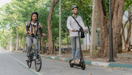 Fototapeta premium Commuting to work with bicycle. Young business person cycling and riding electric scooter to office in downtown district. Modern diversity people use eco transportation in city. Sustainable lifestyle.