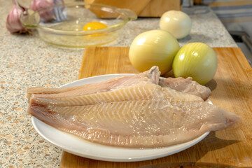 Cleaned carcasses of fresh fish for further preparation against the background of onion heads and a...