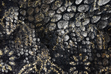 Black dark fabric background with gilding, gold flower patterns with reflective plastic scales.