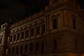 A large building with numerous windows is beautifully illuminated during the night, creating a stunning visual spectacle after sunset