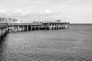 Swanage, Dorset, England, UK - 18 April 2021: Swanage Pier, Victorian pier on the eastern coast of the Isle of Purbeck in black and white