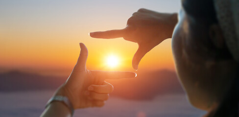 Close up of female hands making frame gesture view distant over sunset. Future planning idea...