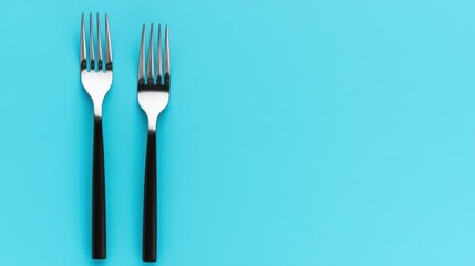 Two forks on a solid turquoise background.
