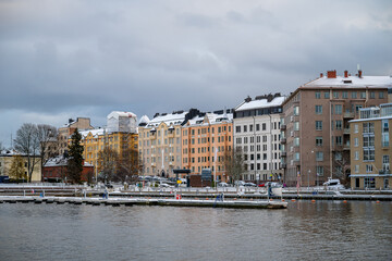 Naklejka premium Snow-covered colorful buildings near a waterfront with cloudy skies in Helsinki, Finland