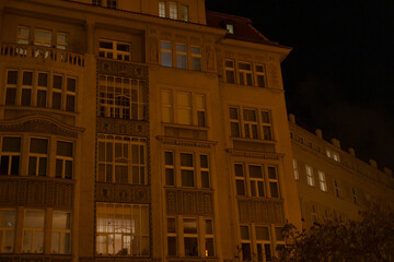 At nighttime, a building that features an abundance of windows is beautifully illuminated, making...