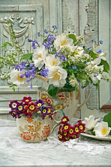 Spring flowers in antique vases still life against a decorative carved wooden background