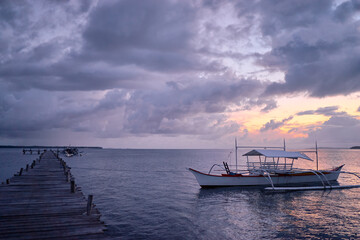Obraz premium Beautiful colorful sunset on the seashore with fishing boats. Philippines, Siargao Island.