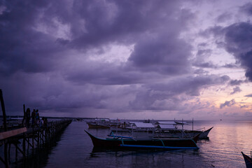 Beautiful colorful sunset on the seashore with fishing boats. Philippines, Siargao Island.